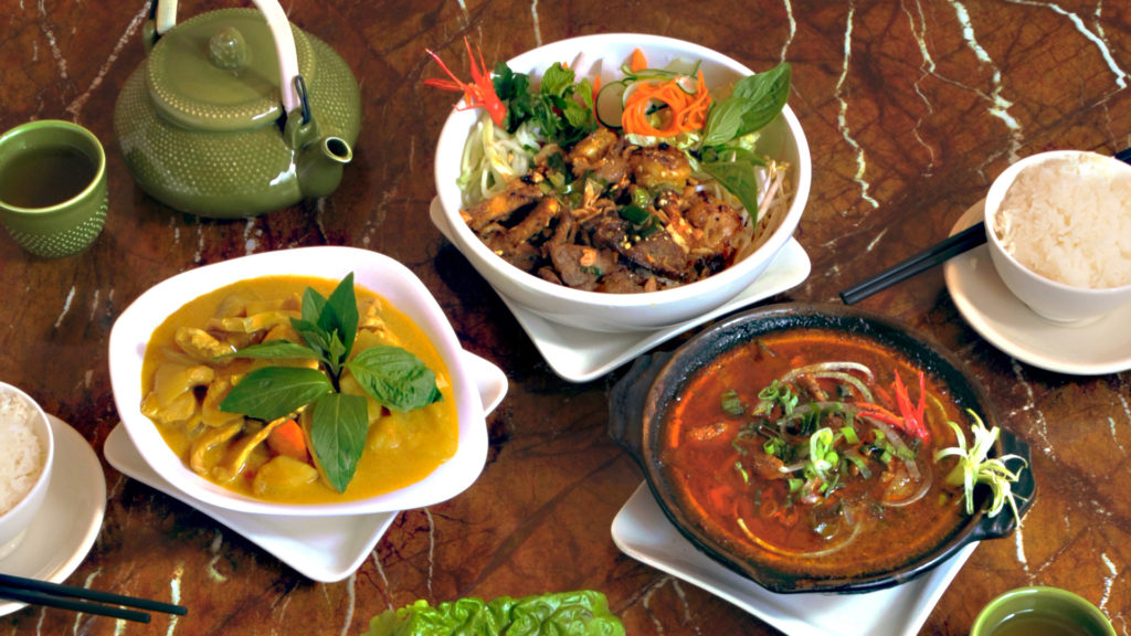 a bowl of curry, viet platter and clay pot with a bowl of rice and a pot of tea